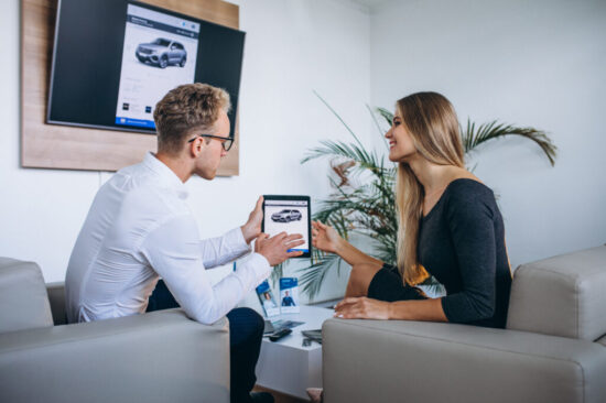 Man and woman in a car showroom using tablet